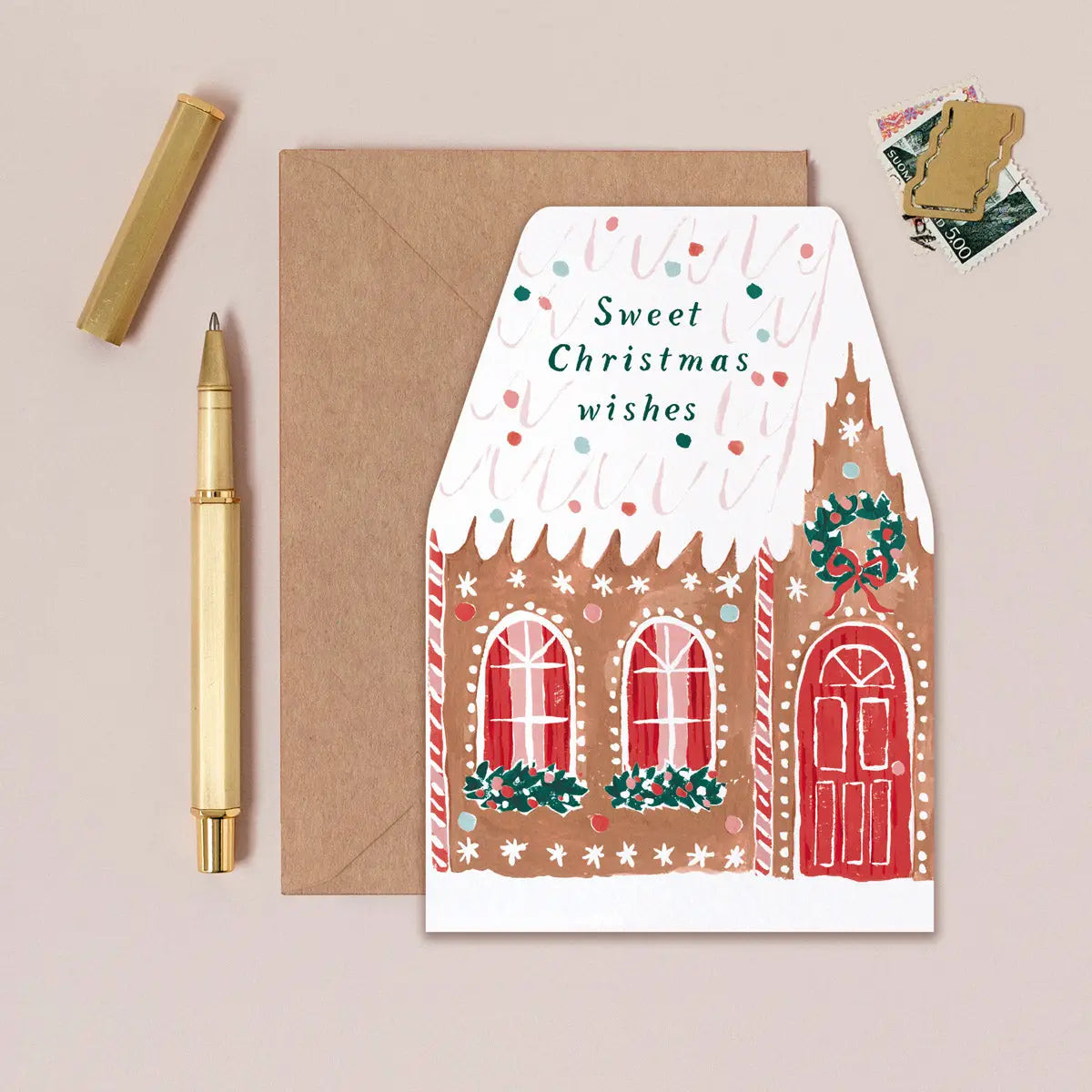 Weihnachtskarte in Lebkuchenhaus-Form mit Zuckerguss-Dach und "Sweet Christmas wishes" auf Kraftpapier-Umschlag