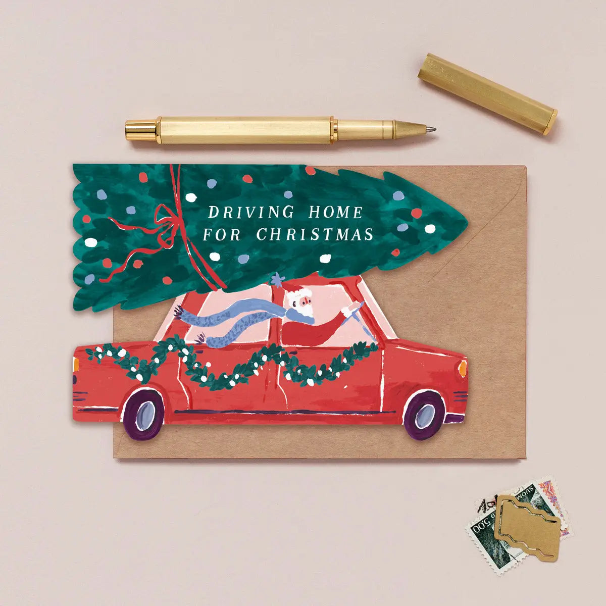 Weihnachtskarte "Driving Home for Christmas" in Form eines roten Autos mit Tannenbaum auf dem Dach, mit Kraftpapier-Umschlag